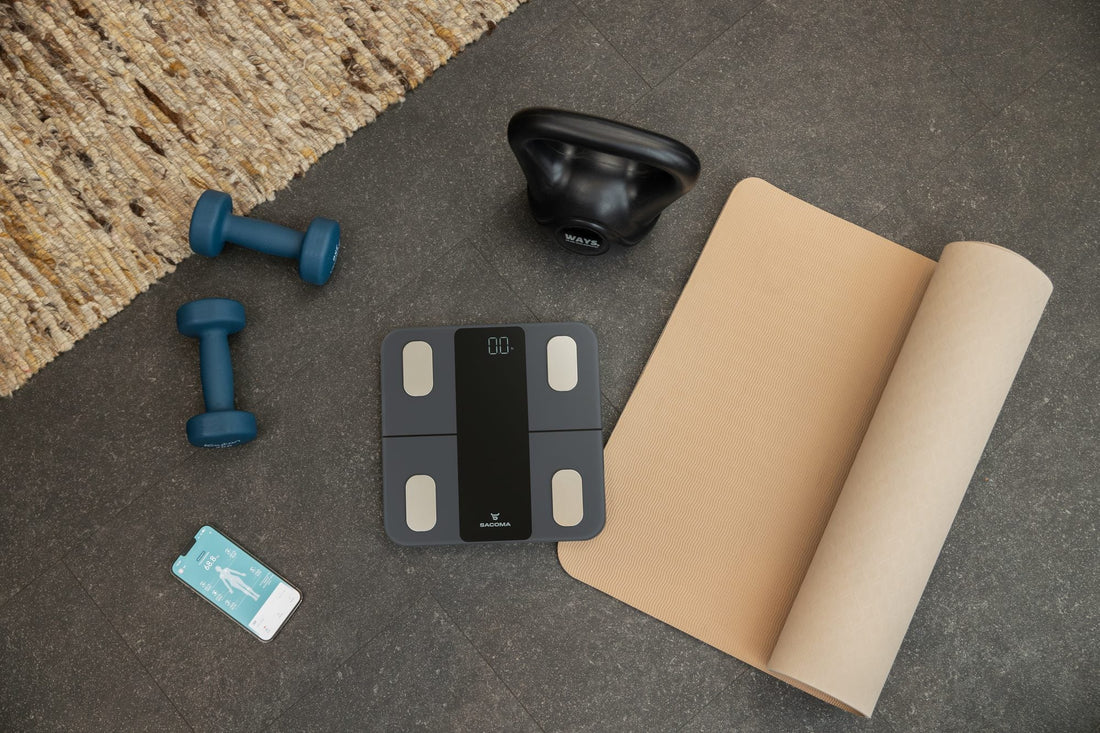 Sacoma slimme weegschaal met yogamat, kettlebell, dumbbells en de app op een telefoon